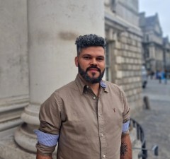 Image of Elwys on Trinity campus wearing a beige and blue striped shirt