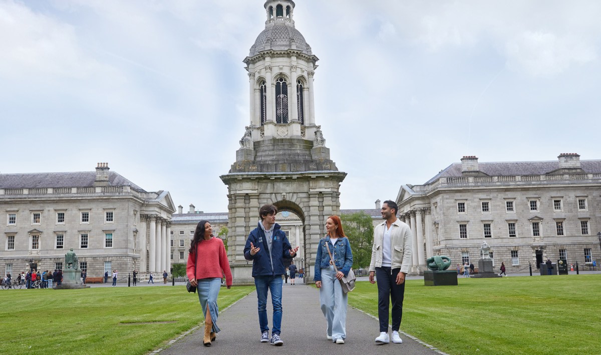 A Trinity guide with three tourists walking through Front Square during the historical walking tour of Trinity College.